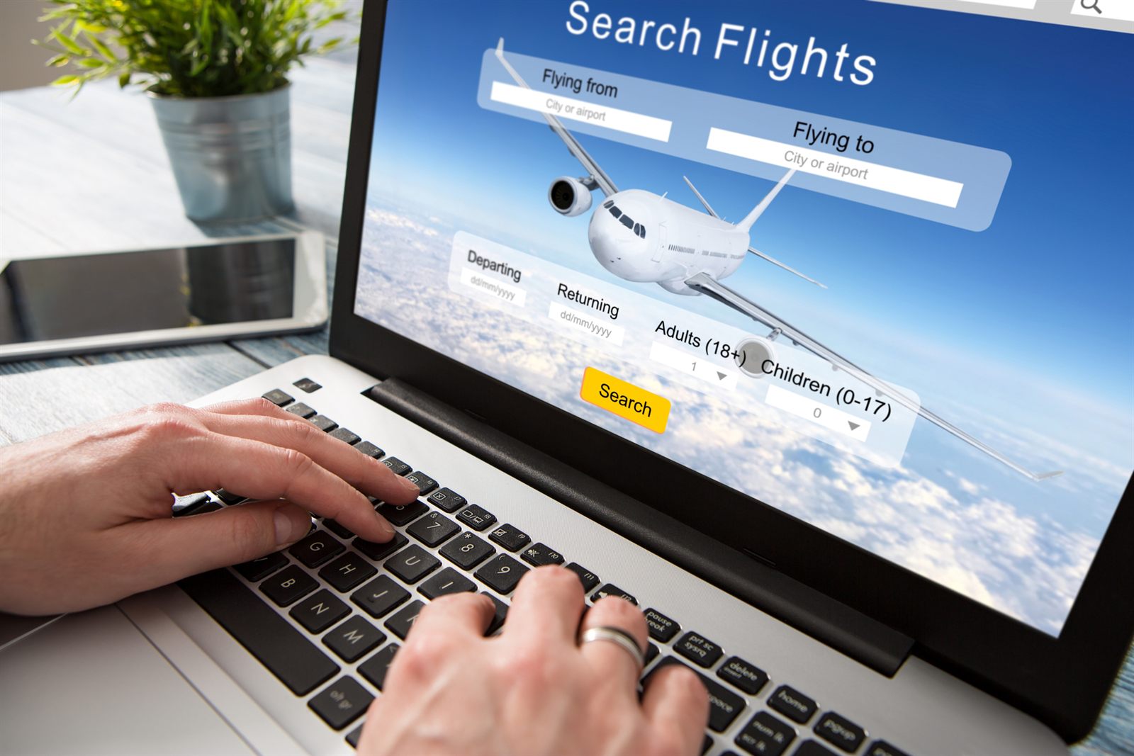 Hands typing on a laptop showing a flight search form