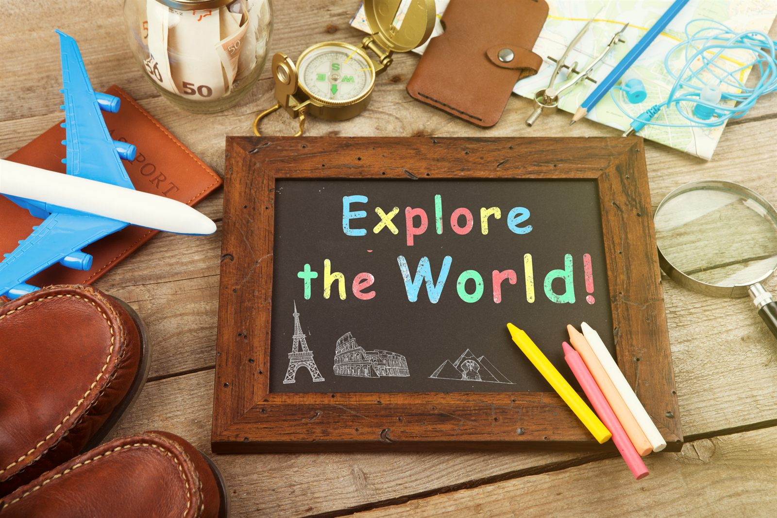 Explore the World chalkboard with leather shoes, a toy plane, compass, wallet and map